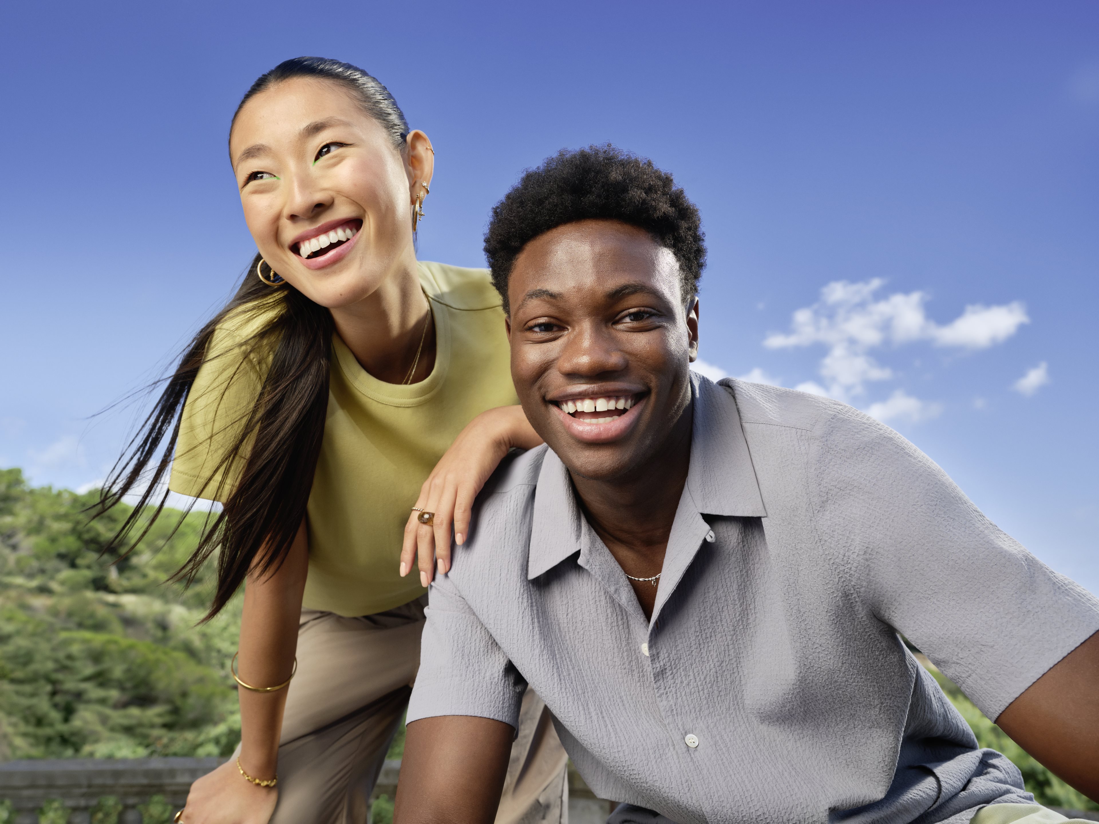 A smiling man and woman in front of a bright blue sky